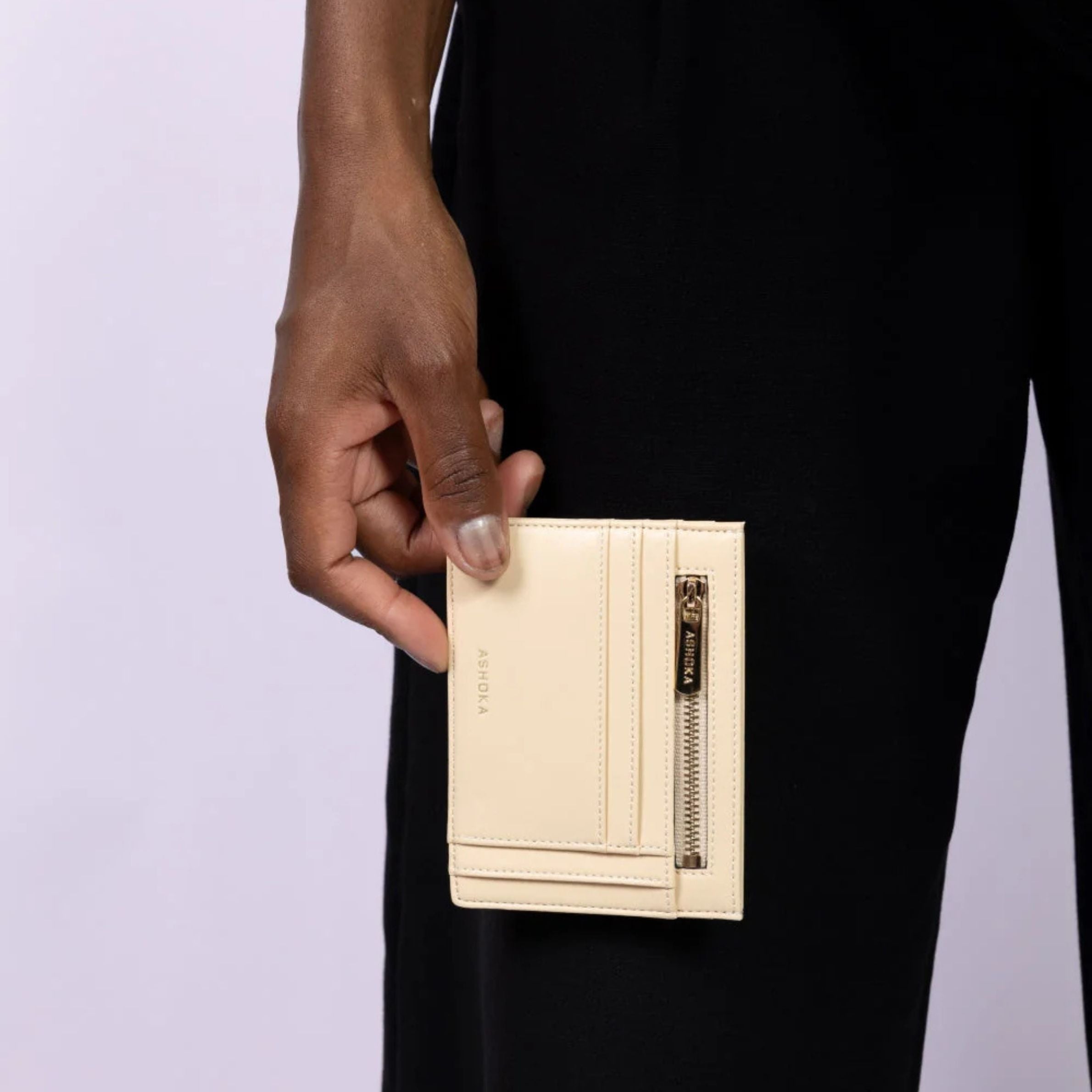 Porte-carte vegan Ashoka Paris en cuir végétal beige avec fermeture zippée, tenu à la main, représentant la collection porte-cartes.