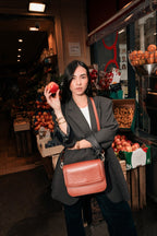 Femme avec un sac en cuir de pomme et une pomme dans la main représentant le Brigitte Couture Camel