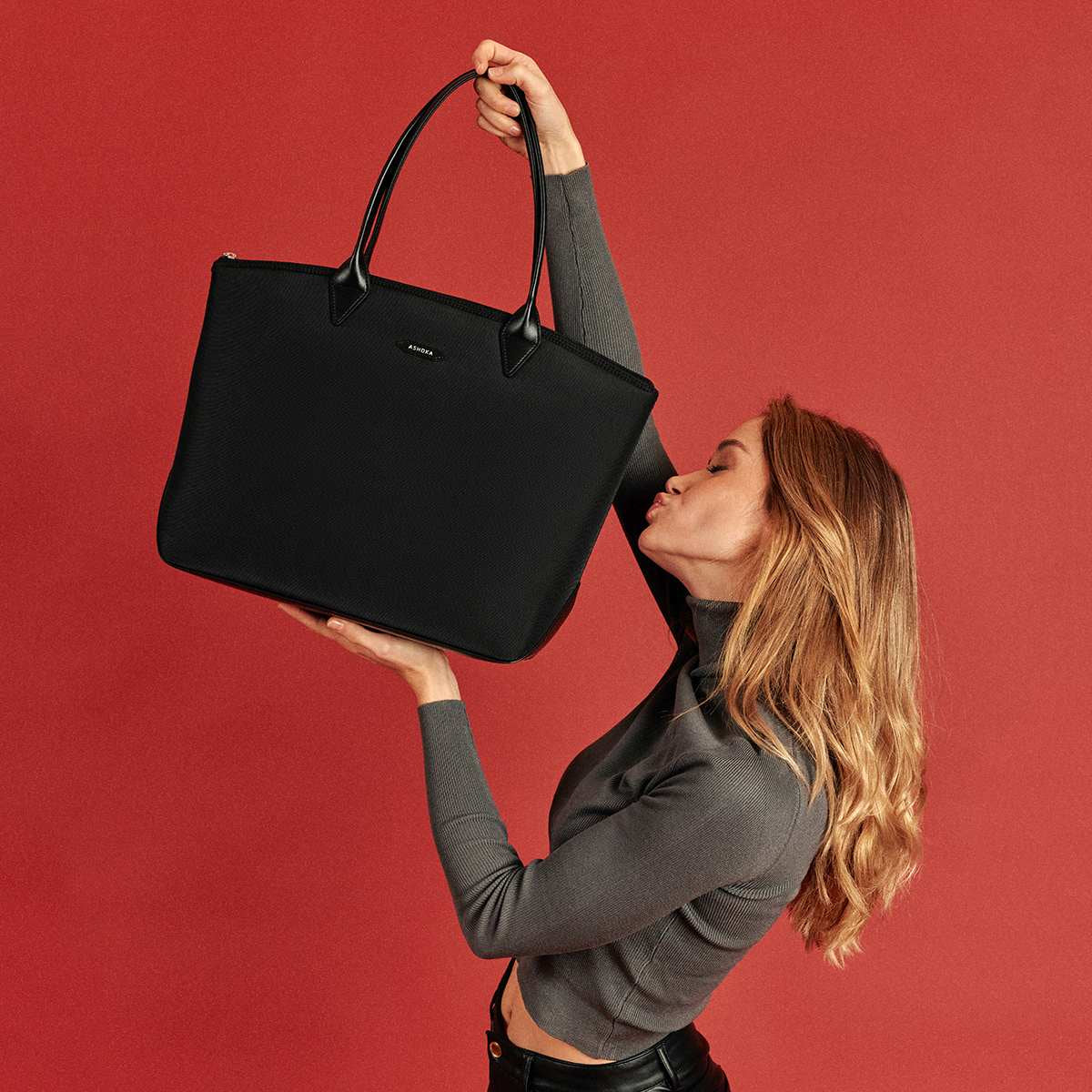 Sac cabas noir intemporel et pratique Ashoka Paris en Uppeal et nylon porté par une femme qui embrasse