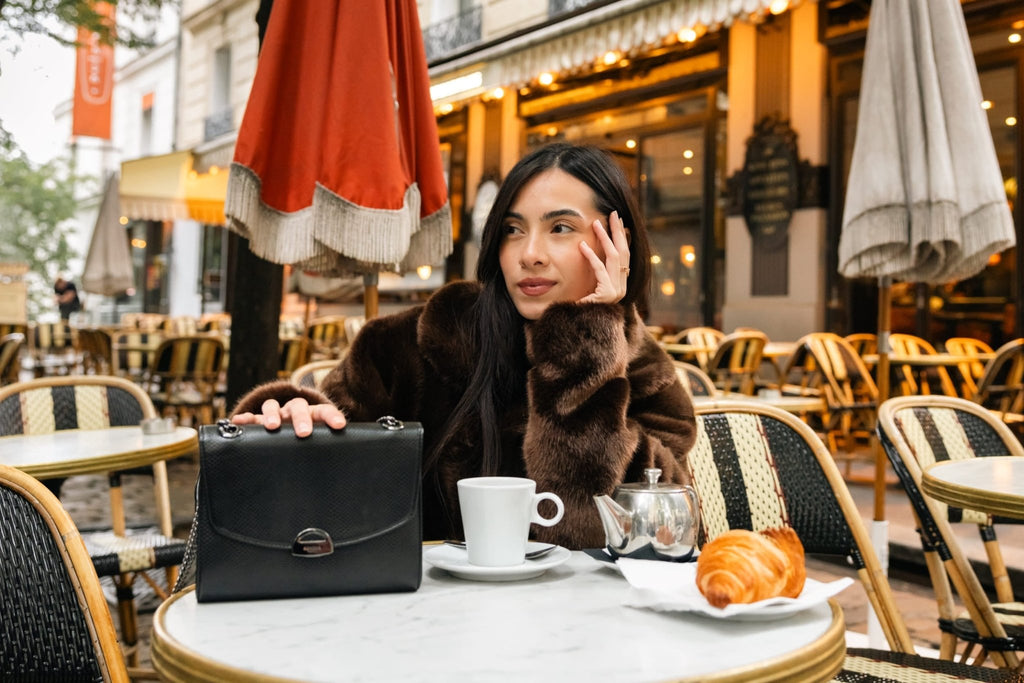 Sac Mini Paname Noir Lézard en cuir végétalien dans un café parisien avec un croissant pour la marque Ashoka Paris