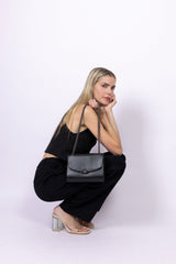 Sac à main vegan noir effet lézard porté par une femme assise, sac bandoulière Mini Paname Ashoka Paris