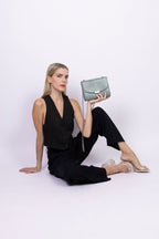 Sac bandoulière vegan bleu-gris effet lézard porté par une femme assise, style chic et responsable